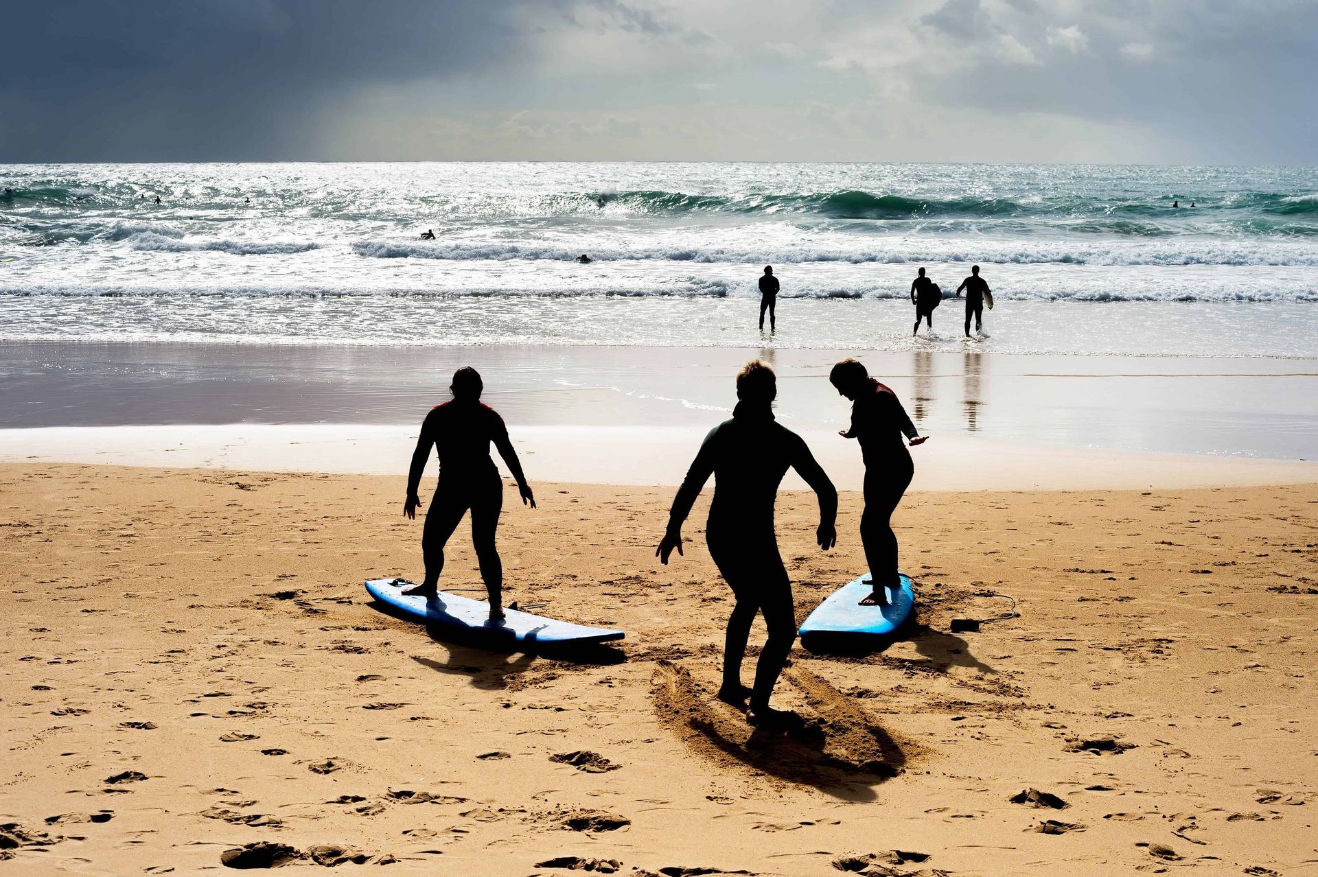 Apprentissage collectif du surf sur la plage, métaphore d’équilibre et de formation