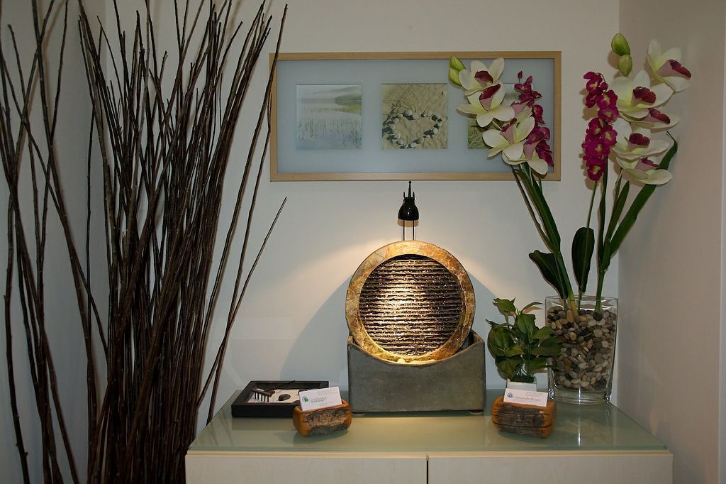 Espace d’accueil zen du cabinet avec fontaine d’eau et décoration florale