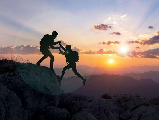 Deux personnes s’entraidant en montagne au coucher du soleil — illustration de nos prestations